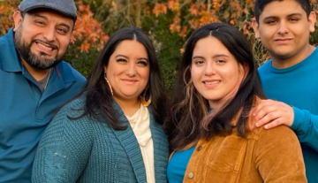 Family photo of a hispanic family dressed in fall colors of teal and brown in front of trees with fall leaves